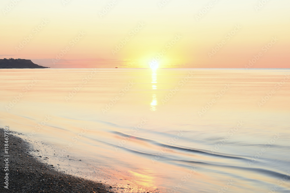 idealistic gentle morning seascape. Water pale pink flowers, because of the rising sun horizon. beautiful summer sea background. In the distance is the Cape.
