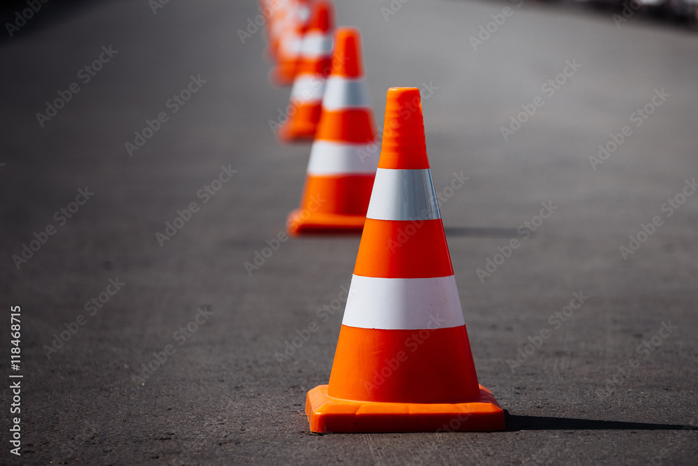 bright orange traffic cones standing in a row on dark asphalt - obrazy, fototapety, plakaty 
