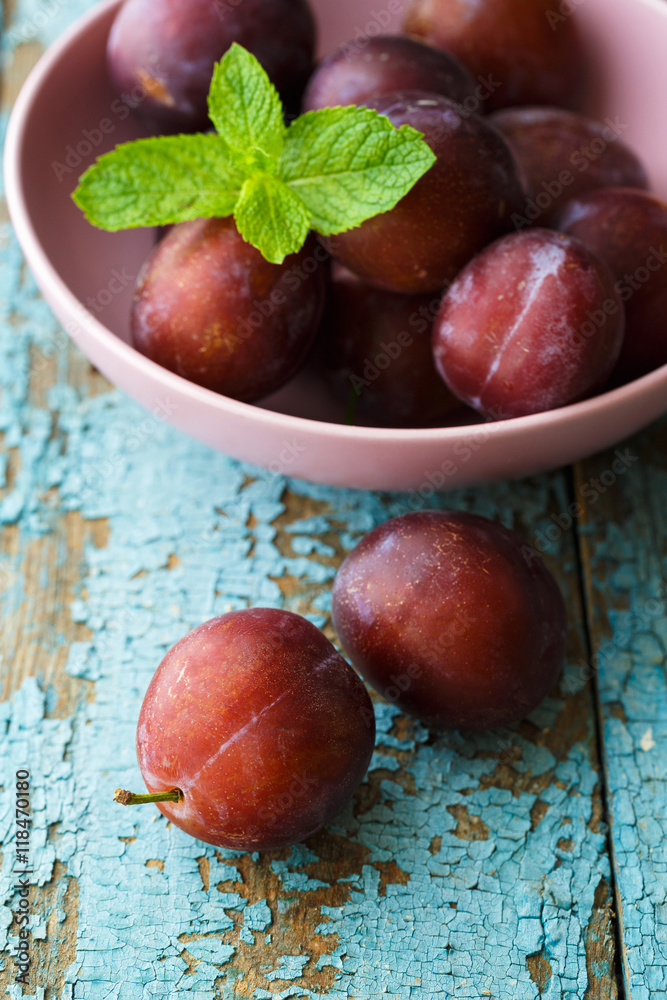 Obraz premium Bowl with plums on blue shabby wooden background