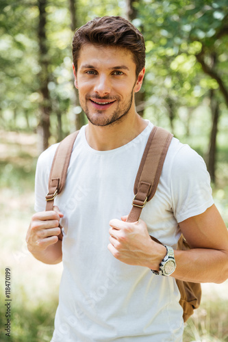 Happy handsome young man with backpack standing outdoors photo