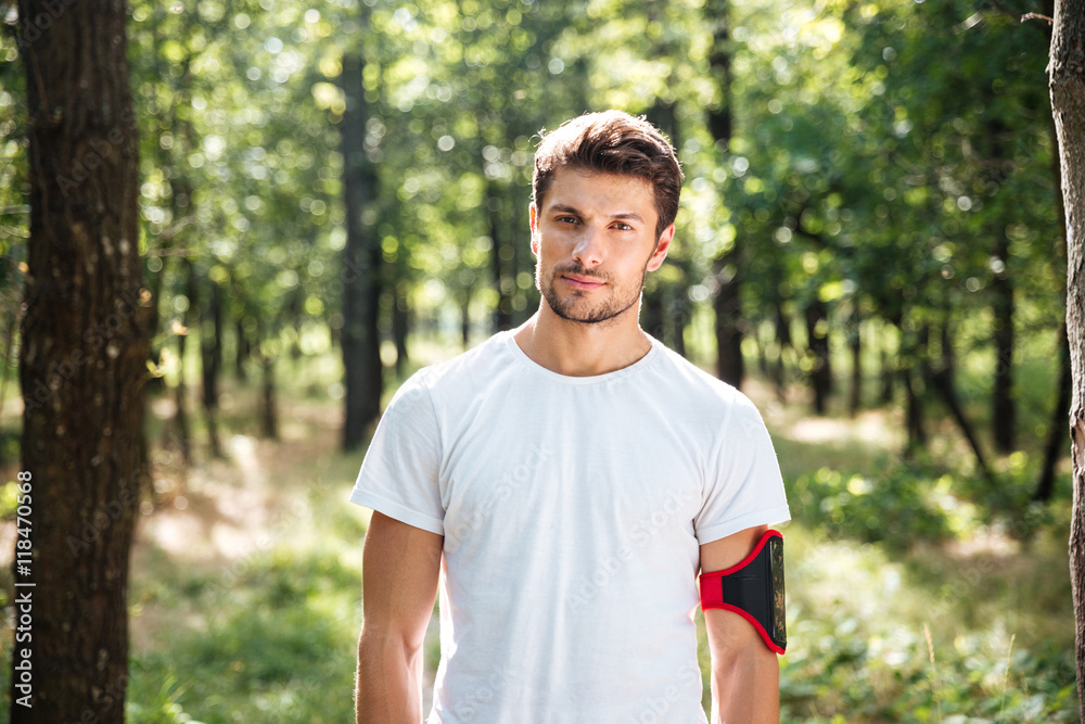 Handsome young man athlete with handband in forest