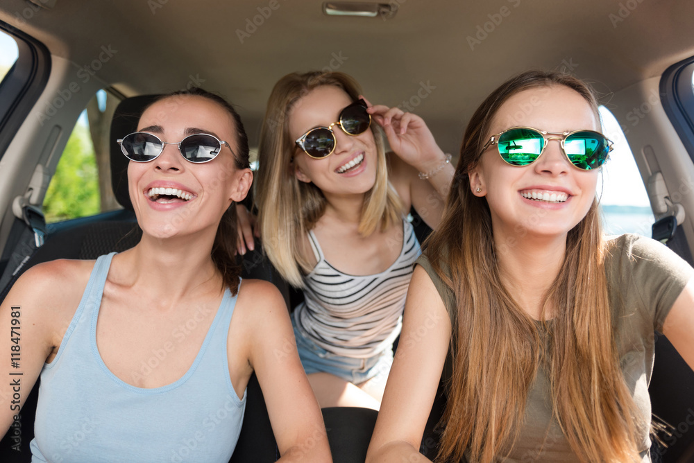 Positive smiling friends driving a car