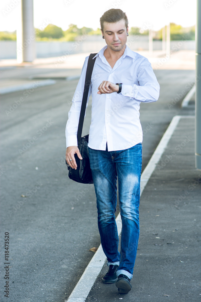 Obraz premium Young stylish man in a hurry looking at his watch