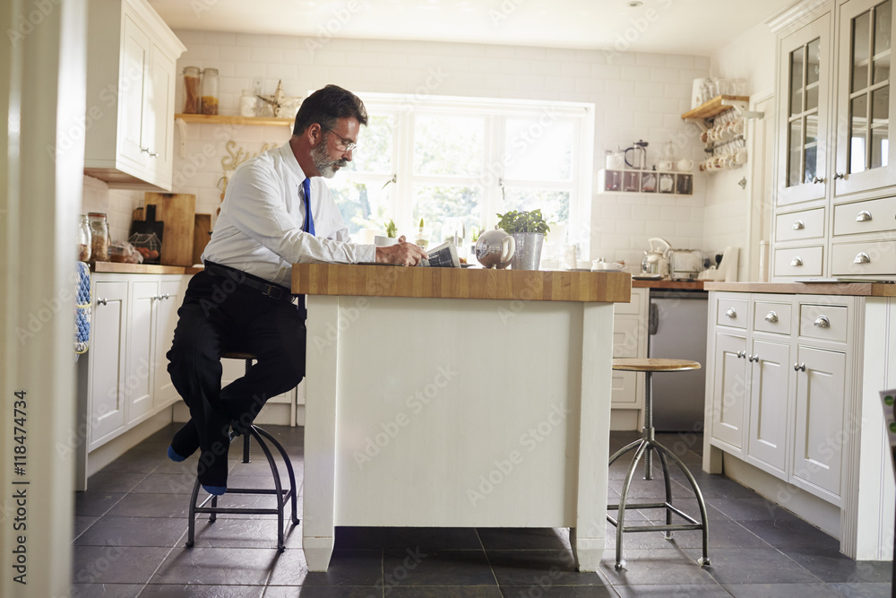 Man sitting at kitchen island reading before work Man sitting at kitchen island reading before work