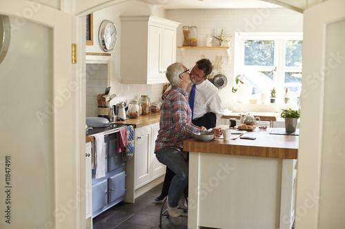 Gay men kissing in kitchen before work, full length photo