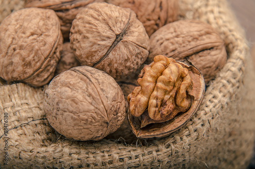 Walnuts on a bag, wooden background, close up