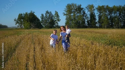 mother with children running in wheat field photo