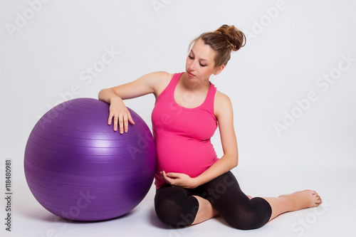 pregnant woman practicing yoga on a light background