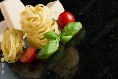 Pasta Tagliatelle  parmesan arranged on marble table. Delicious dry uncooked ingredients for traditional Italian cuisine dish. Raw closeup background. Top view. Copy space