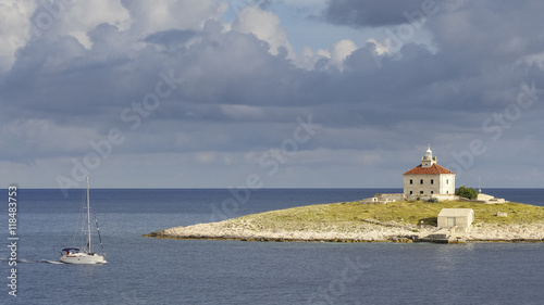 Sdegelschiff kreuzt vor einer Insel mit Leuchtturm photo