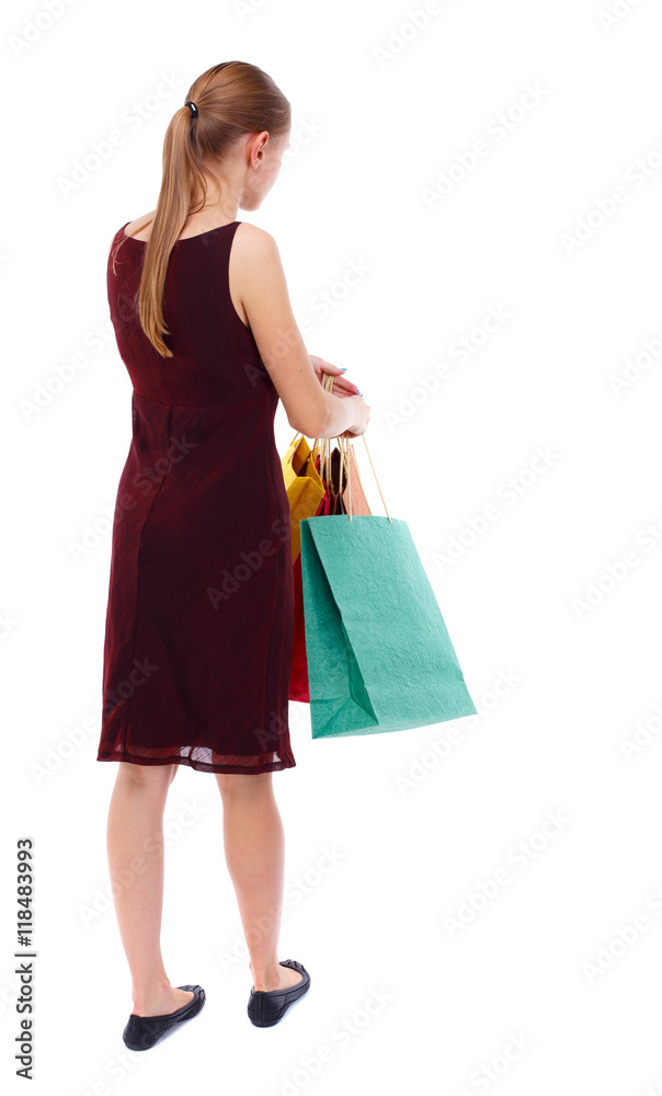 back view of woman with shopping bags. backside view of person.  Rear view people collection. Isolated over white background. Slim blonde in a burgundy dress holding shopping bags.