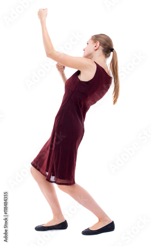 back view of standing girl pulling a rope from the top or cling to something. girl watching. Rear view people collection. backside view of person. Isolated over white background. A girl in a