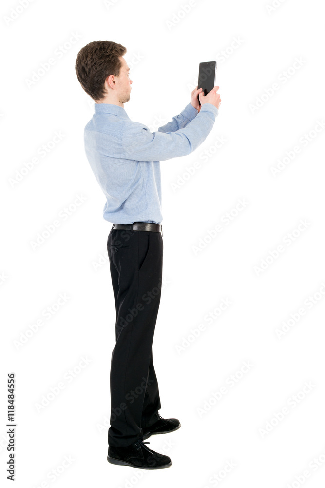 back view of standing business man photographing a phone or tablet. Rear view people collection. backside view of person. Isolated over white background. The curly-haired businessman in light shirt back view of standing business man photographing a phone or tablet. Rear view people collection. backside view of person. Isolated over white background. The curly-haired businessman in light shirt