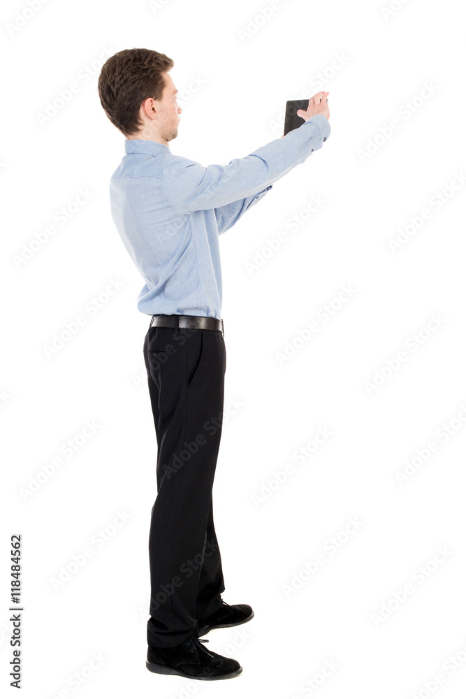 back view of standing business man photographing a phone or tablet. Rear view people collection. backside view of person. Isolated over white background. The curly-haired businessman in light shirt back view of standing business man photographing a phone or tablet. Rear view people collection. backside view of person. Isolated over white background. The curly-haired businessman in light shirt