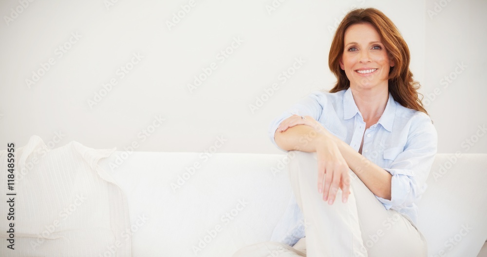 Smiling mature woman sitting on sofa Smiling mature woman sitting on sofa
