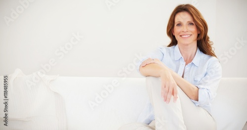Smiling mature woman sitting on sofa