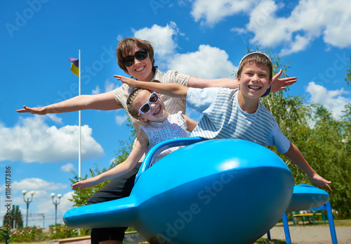 Obraz na plátně child and woman fly on blue airplane attraction in park, happy family having fun