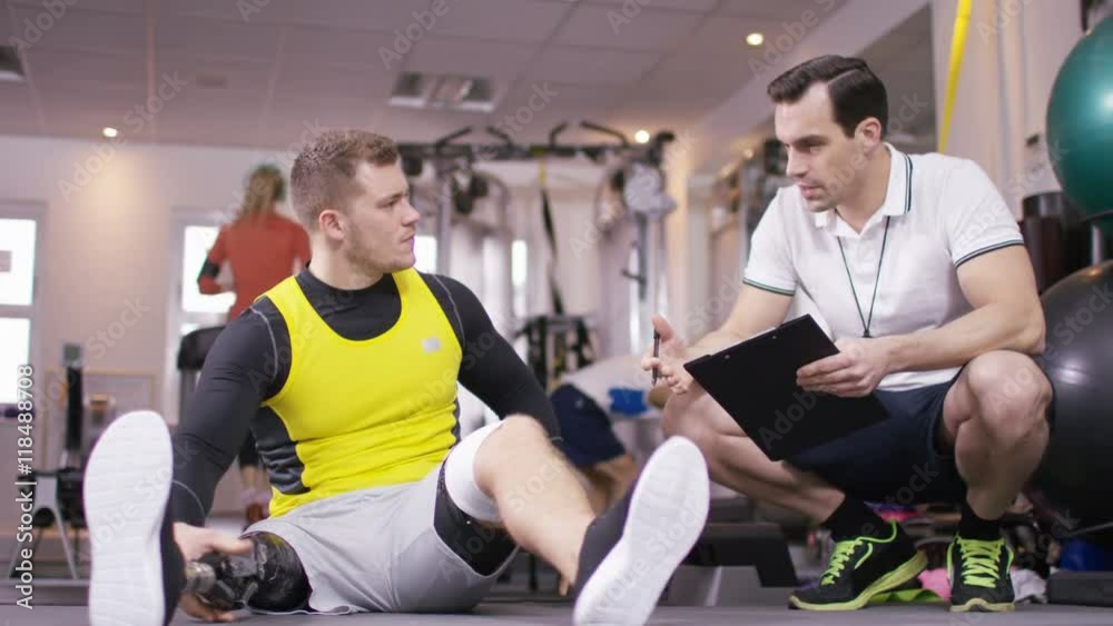 Man with prosthetic leg working out at the gym with personal trainer Man with prosthetic leg working out at the gym with personal trainer