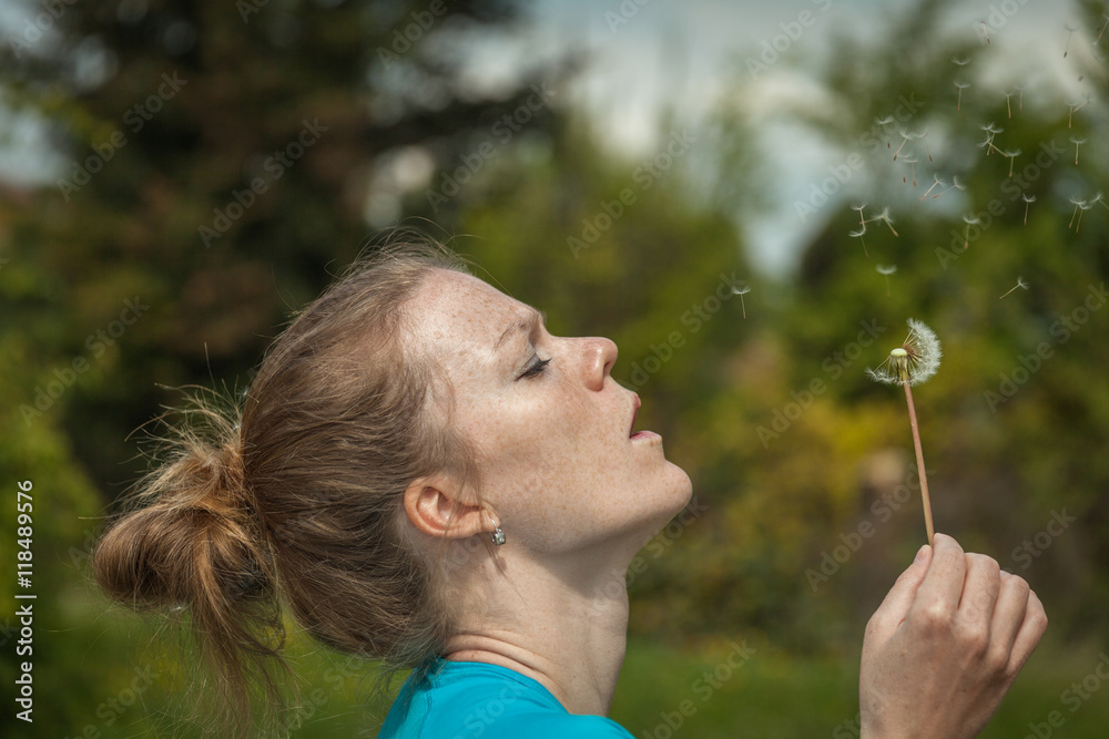 Portrait of young beautiful blonde blowing on a dandelion Portrait of young beautiful blonde blowing on a dandelion