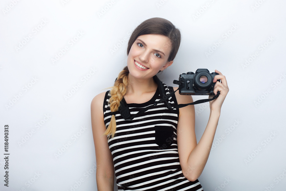 Portrait of happy young beautiful woman in striped shirt posing with black photo camera against studio background Portrait of happy young beautiful woman in striped shirt posing with black photo camera against studio background