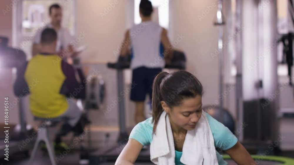 Woman takes a break from training at the gym to rehydrate with bottled water. Woman takes a break from training at the gym to rehydrate with bottled water.