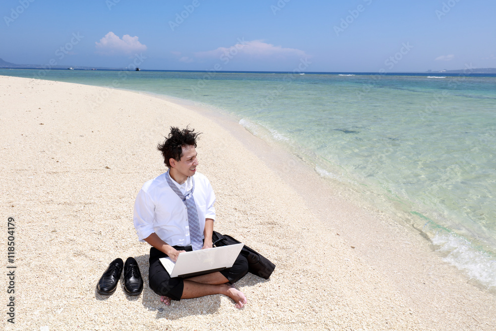美しいビーチでパソコンを楽しむ男性