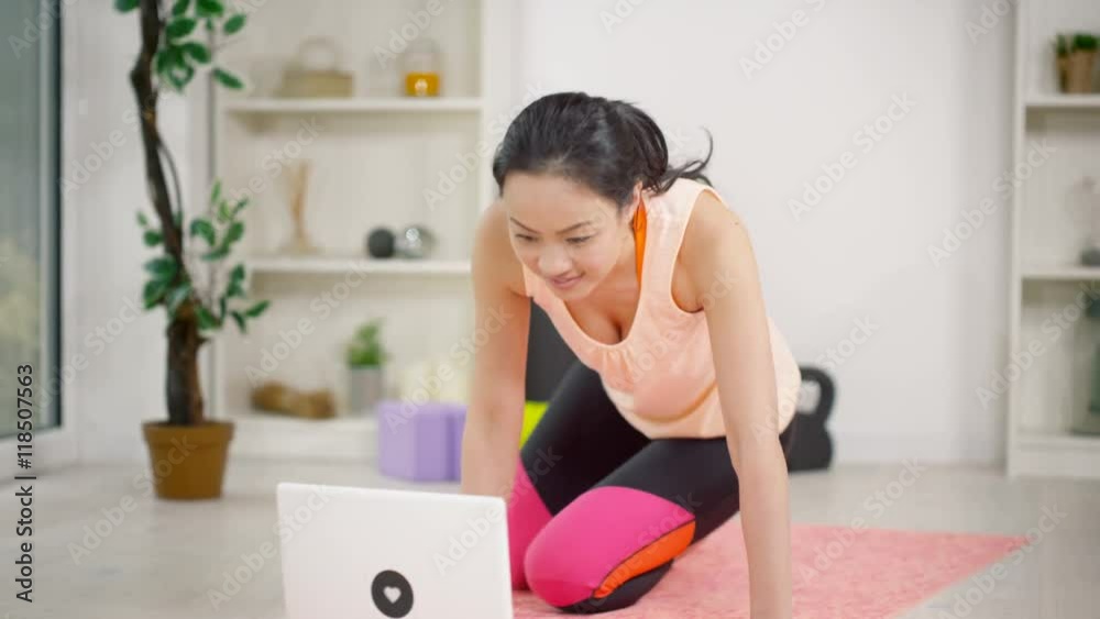 Young woman using a laptop computer to follow a workout at home Young woman using a laptop computer to follow a workout at home