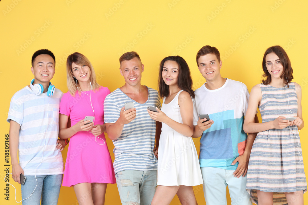 Happy teenagers with gadgets on yellow background Happy teenagers with gadgets on yellow background