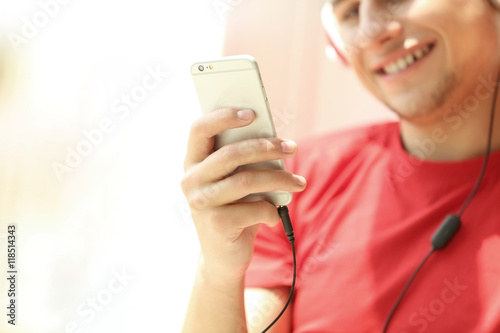 Young man listening to music on smartphone in the room