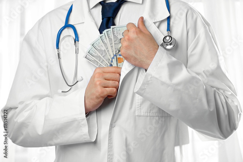 Doctor putting money in his coat pocket closeup