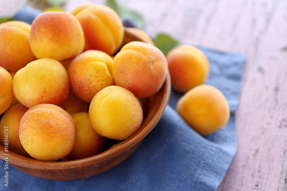 Fresh juicy apricots in bowl on wooden table Fresh juicy apricots in bowl on wooden table