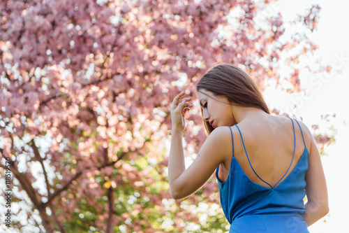 Beautiful young woman standing near the apple tree.