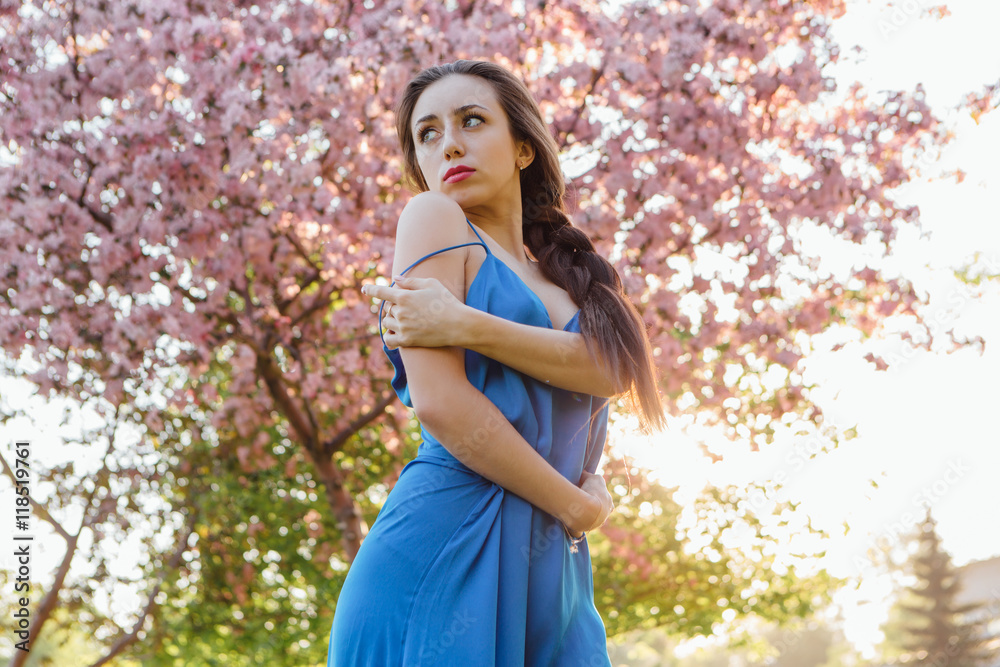 Beautiful young woman standing near the apple tree.