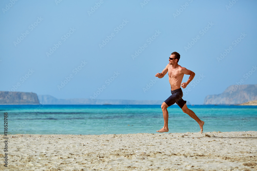 strong athletic man with bared torso running on the beach along the sea front strong athletic man with bared torso running on the beach along the sea front