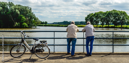 Obraz na płótnie Two elderly men leaning over a bridge railing w salonie