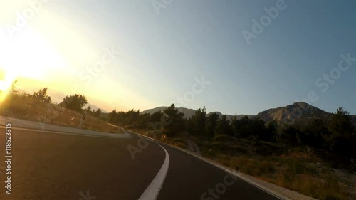 Motorcycle driving on road at sunset point of view