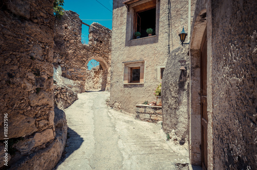 Fototapeta Naklejka Na Ścianę i Meble -  Old narrow street with stone arch at Maroulas, Crete 