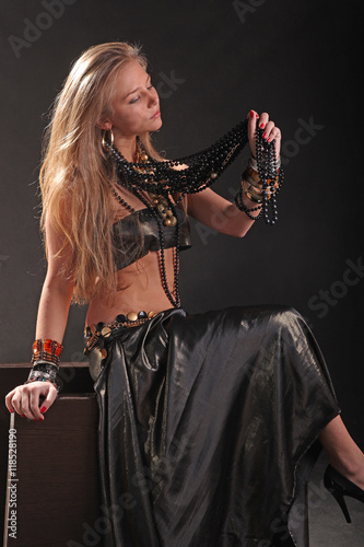 young girl in beads and bracelets on black background