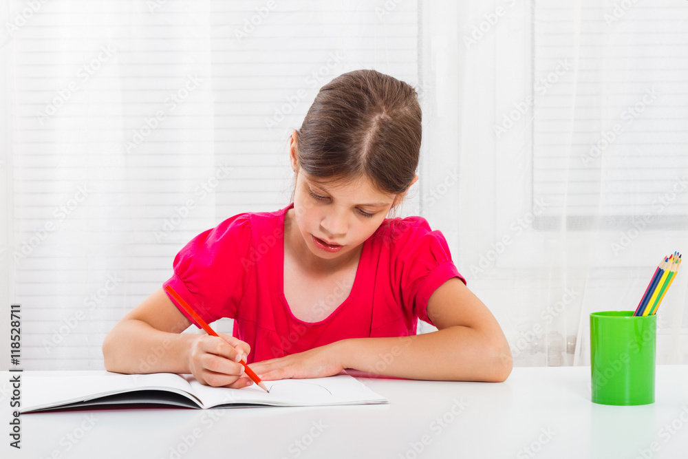 Cute little girl enjoys drawing and writing at her home.
Cute little girl enjoys drawing and writing at her home.