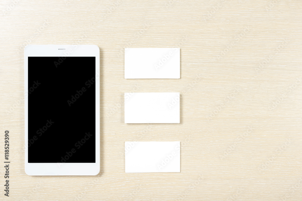 Business card blank and smartphone or tablet pc at office desk table top view. Corporate stationery branding mock-up Business card blank and smartphone or tablet pc at office desk table top view. Corporate stationery branding mock-up