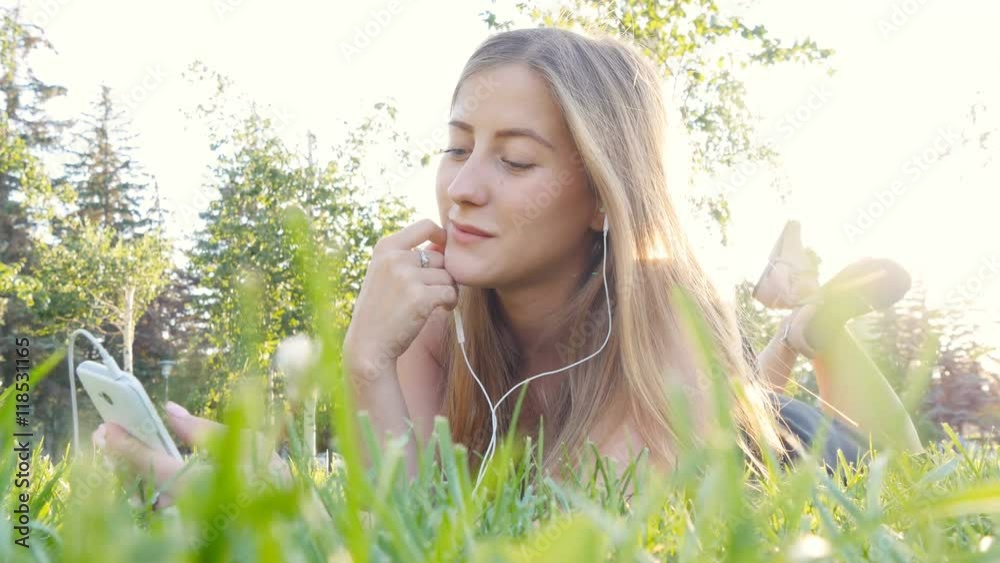 Young woman touching cell phone and lying on meadow Young woman touching cell phone and lying on meadow