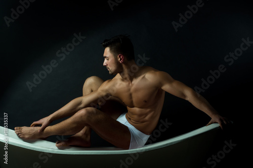 Muscular man on bathtub