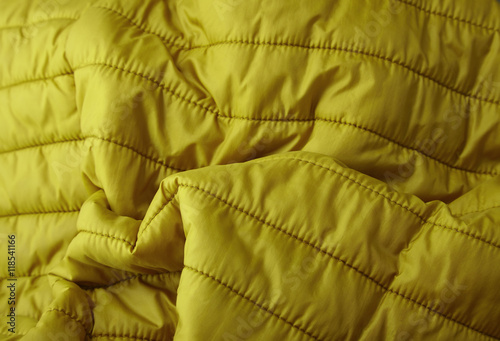 A full page close up of quilted yellow sleeping bag fabric texture