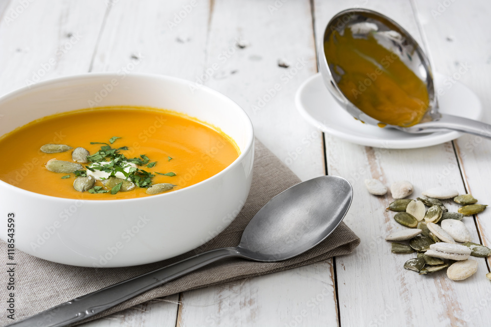 Pumpkin soup in bowl on a white wooden table
Pumpkin soup in bowl on a white wooden table