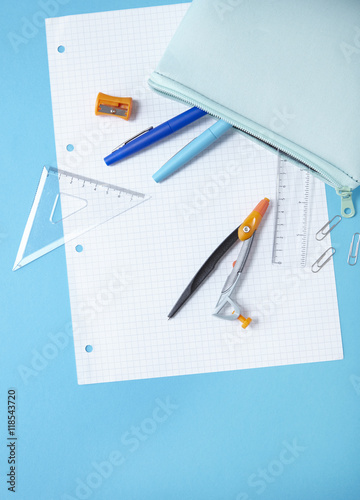 A pastel colored pencil case with stationery spilling out on to a blue background, forming a page border