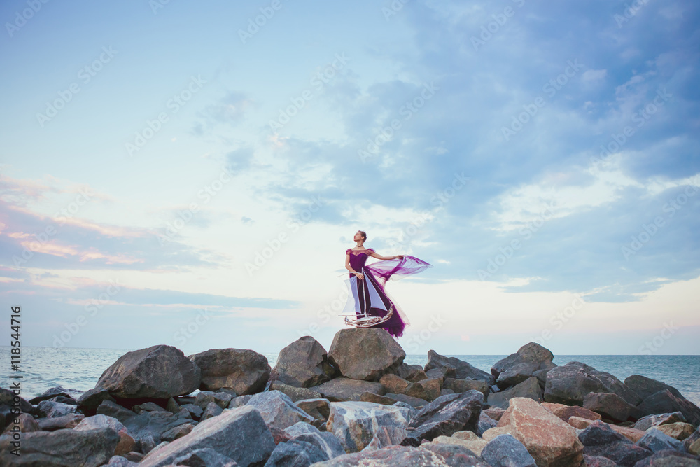 Obraz premium Young romantic woman posing on the beach watching the sunset