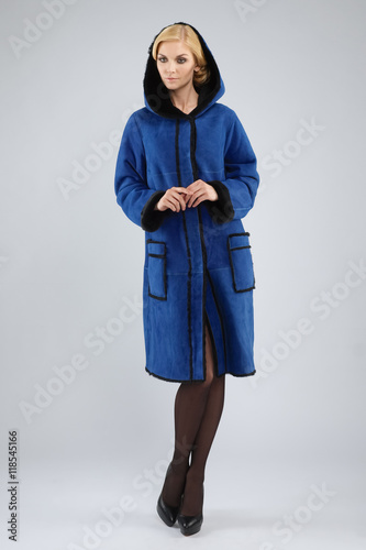 Attractive lady in long blue leather coat with fur posing