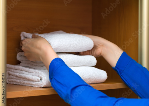 Room service. Woman changing towels in cabinet. photo