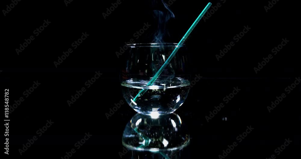 A glass which is half full with water is standing on a table in the kitchen. A green straw falls into it. Wide-angle shot.
A glass which is half full with water is standing on a table in the kitchen. A green straw falls into it. Wide-angle shot.