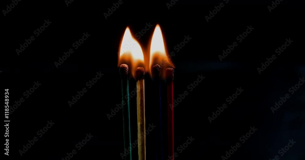 A few matches are together and they are burning nicely. They are of different colours. Close-up shot.
